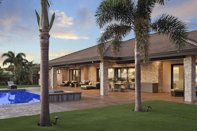 pool at dusk with ceiling fan, an outdoor hangout area, a yard, and a patio