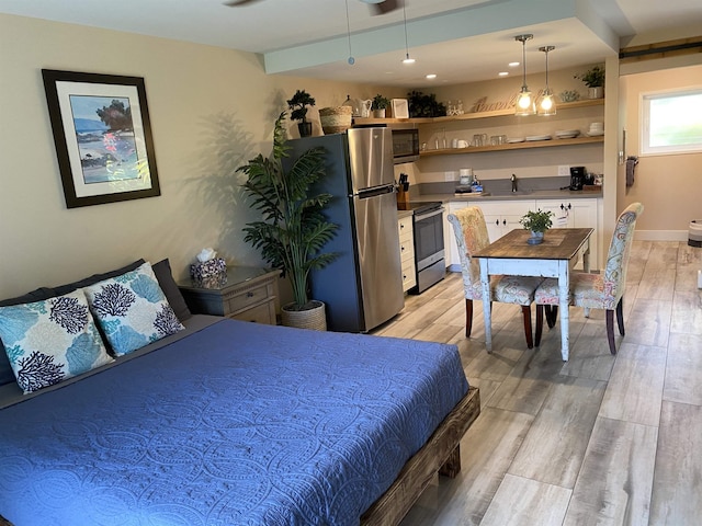 bedroom featuring beamed ceiling, a sink, freestanding refrigerator, light wood-style floors, and baseboards