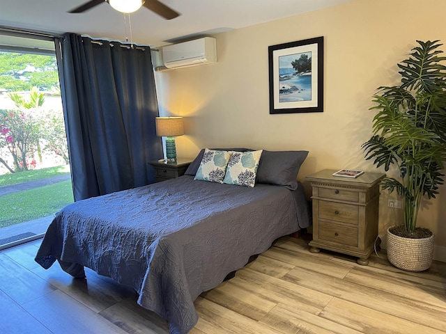 bedroom featuring access to exterior, light wood-style flooring, a wall mounted air conditioner, and ceiling fan