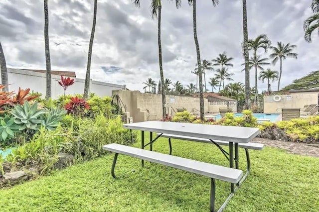 view of home's community with a swimming pool, a yard, and fence