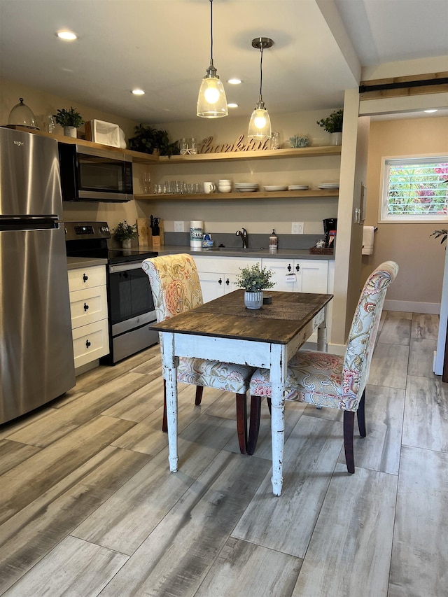 kitchen with dark countertops, light wood-style flooring, appliances with stainless steel finishes, white cabinetry, and open shelves