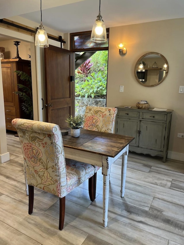 dining area with light hardwood / wood-style flooring and a barn door