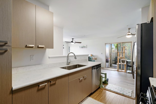 kitchen with stainless steel appliances, a ceiling fan, light wood-style flooring, and a sink