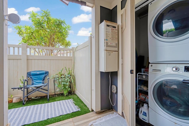 laundry area featuring stacked washer / drying machine, wood finished floors, and laundry area