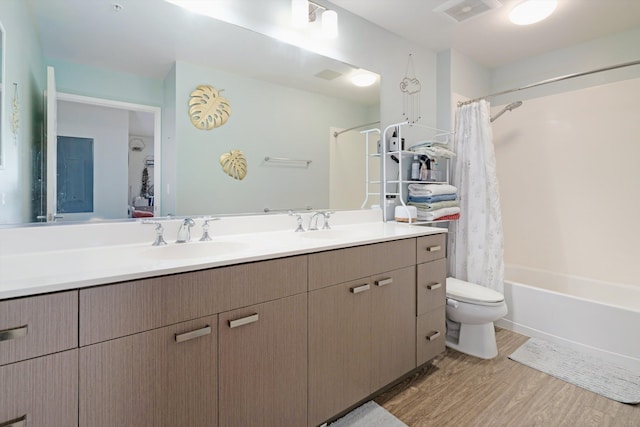 bathroom featuring a sink, double vanity, visible vents, toilet, and wood finished floors