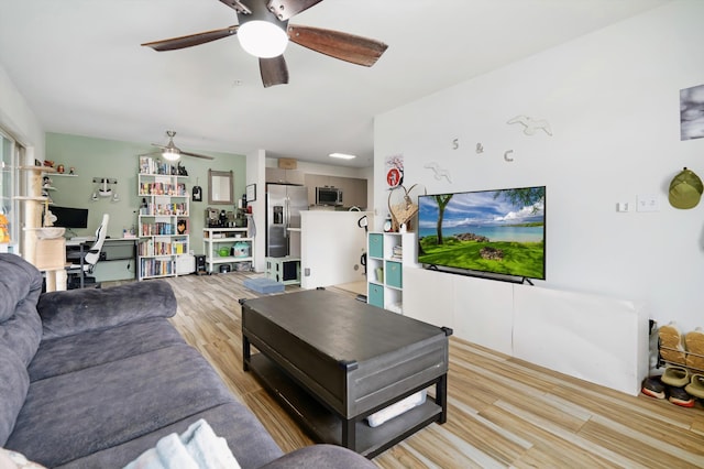 living room with a ceiling fan and light wood-style flooring