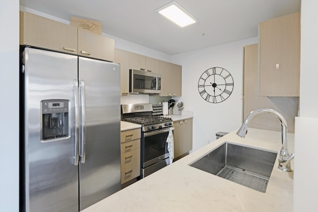 kitchen with light stone countertops, cream cabinetry, appliances with stainless steel finishes, and a sink