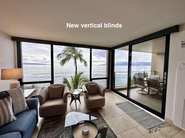 living room featuring floor to ceiling windows, a water view, and light tile patterned floors