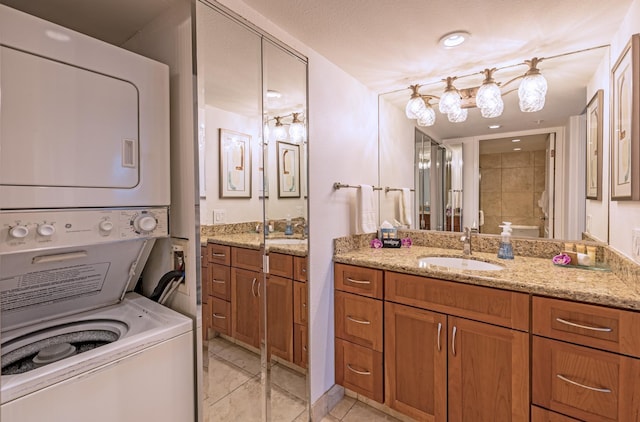 bathroom featuring tile patterned flooring, stacked washer and clothes dryer, and vanity