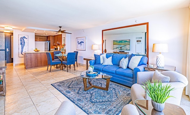 living room featuring ceiling fan, baseboards, and light tile patterned floors