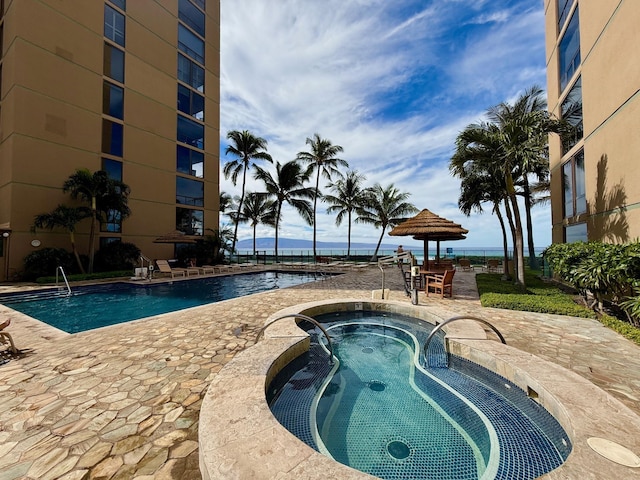 community pool with a hot tub and a patio