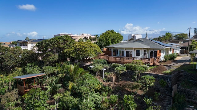 back of property featuring a wooden deck and solar panels