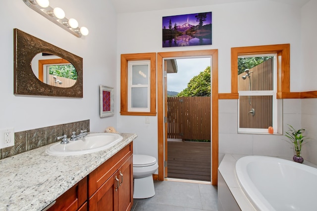 bathroom with tile patterned flooring, vanity, a relaxing tiled tub, and toilet