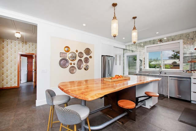 kitchen featuring crown molding, sink, hanging light fixtures, white cabinetry, and stainless steel appliances