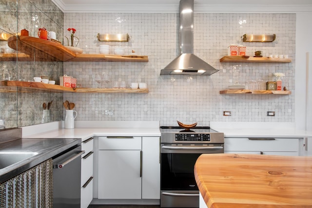 kitchen featuring decorative backsplash, white cabinetry, wall chimney range hood, and stainless steel range