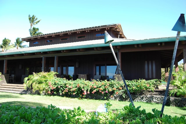 rear view of house with metal roof, a yard, and board and batten siding