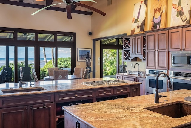 kitchen with stainless steel appliances, light stone counters, and a sink