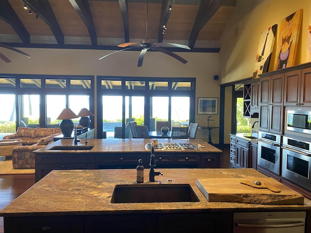 kitchen featuring appliances with stainless steel finishes, open floor plan, a sink, and an island with sink