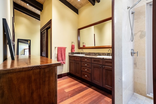 full bath featuring double vanity, a sink, and beam ceiling