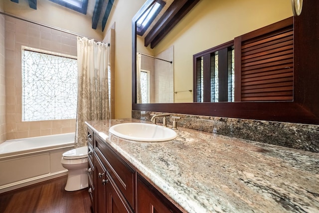 full bathroom featuring wood finished floors, shower / bath combo with shower curtain, vanity, and toilet