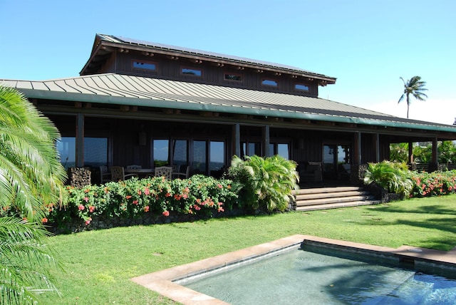 rear view of property featuring a standing seam roof, a yard, and metal roof