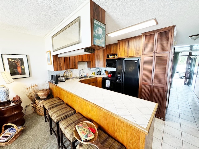 kitchen featuring kitchen peninsula, black appliances, and a textured ceiling