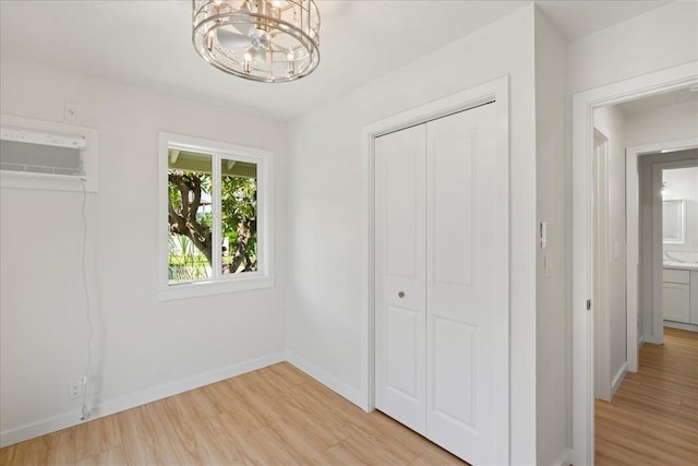 2825 Kauhale St, Kihei, HI 96753 - unfurnished bedroom featuring a chandelier, an AC wall unit, light wood-type flooring, and a closet