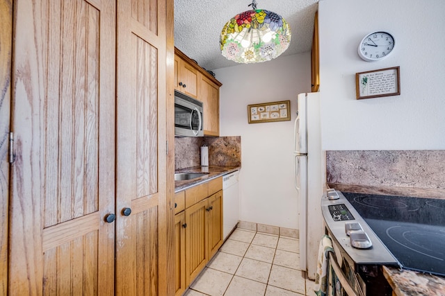 kitchen featuring appliances with stainless steel finishes, a textured ceiling, sink, light tile flooring, and backsplash