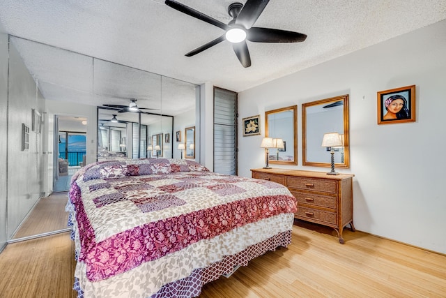 bedroom with light hardwood / wood-style flooring, ceiling fan, and a textured ceiling