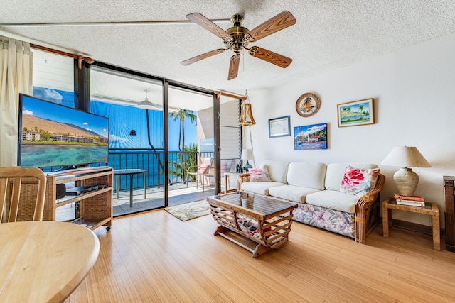 living room with wood-type flooring, a textured ceiling, ceiling fan, and floor to ceiling windows