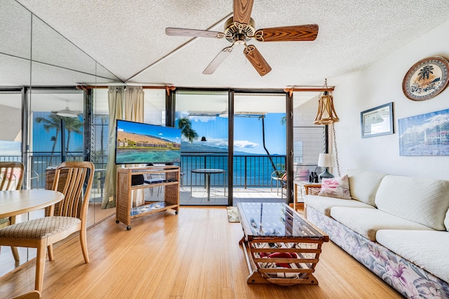 living room featuring hardwood / wood-style flooring, ceiling fan, a textured ceiling, and expansive windows