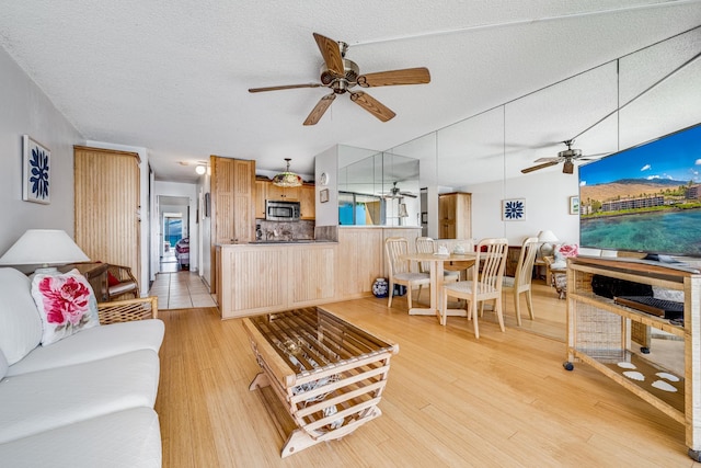 living room featuring ceiling fan, light tile flooring, and a textured ceiling