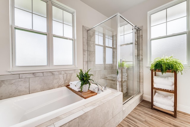 bathroom featuring plenty of natural light, independent shower and bath, and hardwood / wood-style flooring