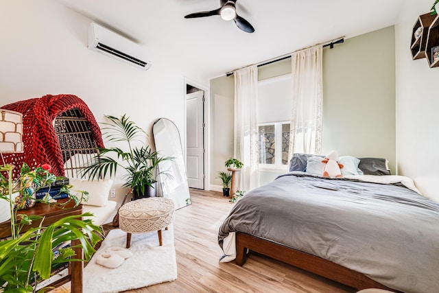 bedroom featuring a wall mounted air conditioner, ceiling fan, and light hardwood / wood-style floors