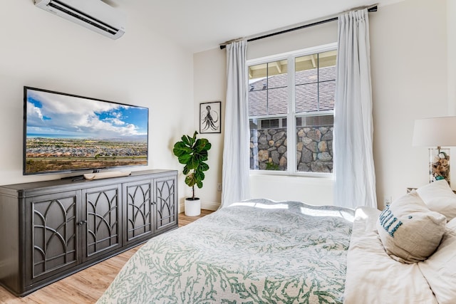 bedroom with light wood-type flooring and an AC wall unit