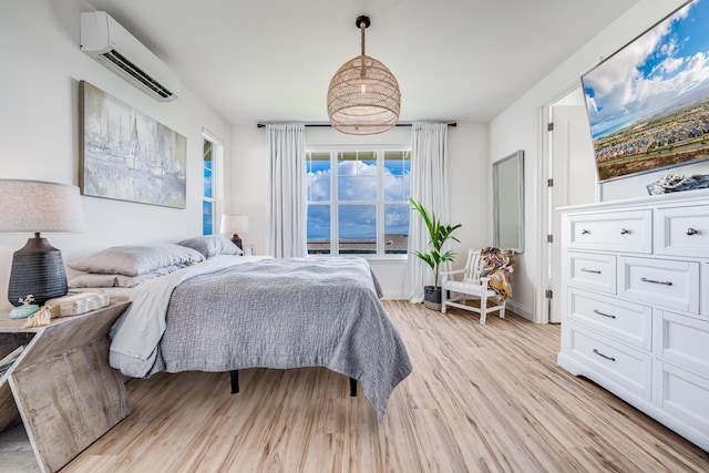 bedroom with a wall unit AC and light wood-type flooring