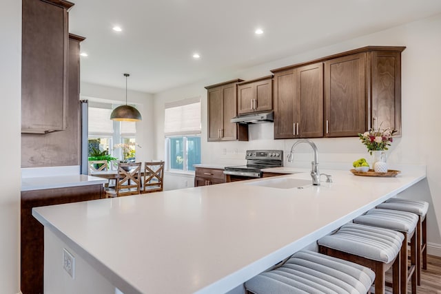 kitchen with kitchen peninsula, sink, electric stove, hardwood / wood-style floors, and hanging light fixtures