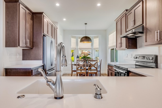 kitchen featuring sink, electric range, hardwood / wood-style floors, stainless steel refrigerator, and hanging light fixtures