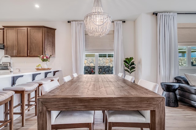 dining room featuring a healthy amount of sunlight, a notable chandelier, and light wood-type flooring