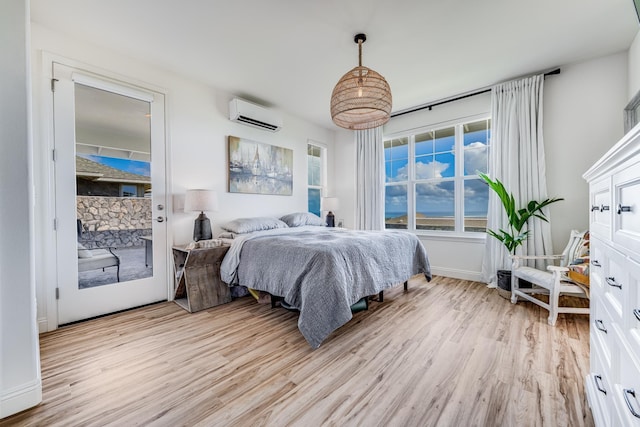 bedroom with a wall mounted air conditioner, access to exterior, and light hardwood / wood-style floors