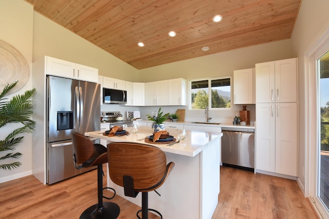 kitchen featuring a center island, stainless steel appliances, vaulted ceiling, and white cabinetry