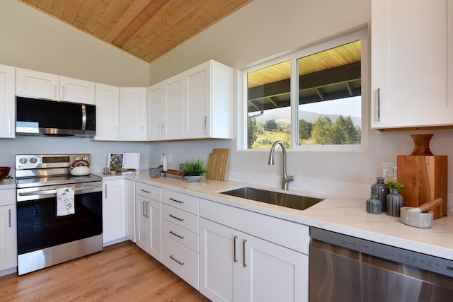 kitchen with stainless steel appliances, sink, white cabinets, light hardwood / wood-style floors, and lofted ceiling