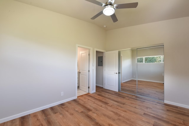 unfurnished bedroom featuring ceiling fan, light hardwood / wood-style flooring, electric panel, a closet, and lofted ceiling