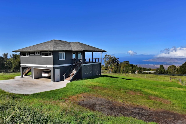 rear view of house with a carport, a mountain view, and a lawn