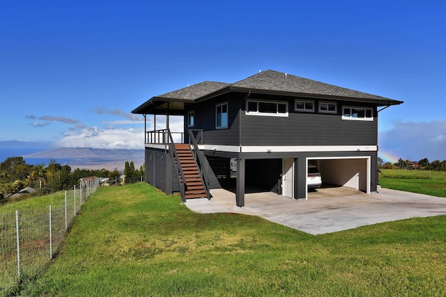 rear view of house with a lawn, a mountain view, and a garage