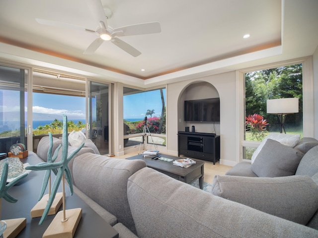 living room featuring ceiling fan and a raised ceiling