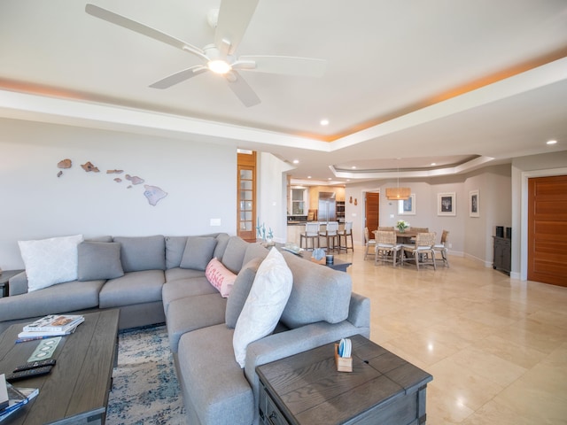 living room with ceiling fan, light tile patterned floors, and a tray ceiling