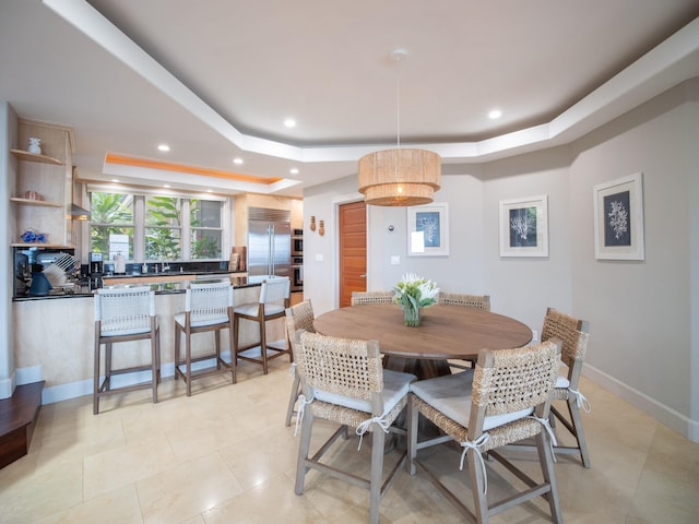 dining area with light tile patterned floors and a tray ceiling