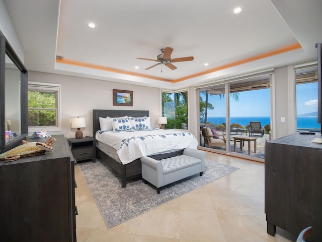 tiled bedroom with access to outside, ceiling fan, a raised ceiling, and a water view