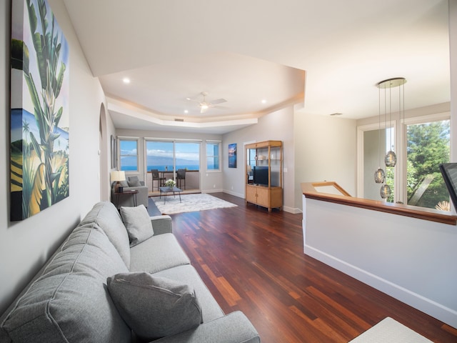 living room featuring dark hardwood / wood-style floors, ceiling fan, and a raised ceiling